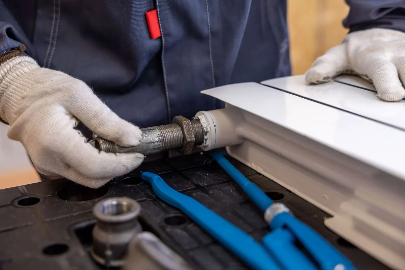 Technician fitting a pipe connection with hand tools
